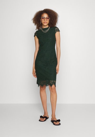Σκούρο πράσινο δαντελένιο φόρεμα με κοντά μανίκια, σα scalloped στρίφωμα και λουλουδάτο σχέδιο. Συνδυασμένο με μαύρες σανδάλες με ρυάκια. Ελάχιστα κοσμήματα.
