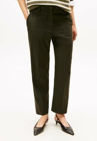 Dark green pinstriped trousers with a straight-leg cut and a smooth texture. Features belt loops and a button closure, paired with black shoes.