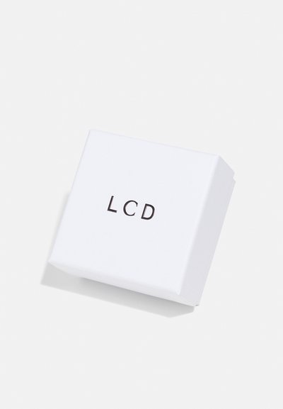 Boîte en carton blanche avec "LCD" imprimé en lettres noires sur le devant, présentant une forme carrée simple et une texture lisse.
