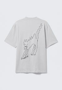 T-shirt en coton blanc avec un dessin au trait noir d'une créature au dos, coupe décontractée et manches courtes.