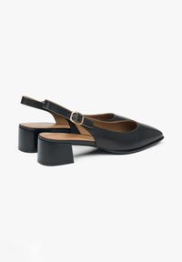 Černé kožené sandály s úzkou špičkou a středně vysokým blokovým podpatkem. Mají sponu a hladký povrch.