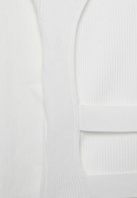 Tissu blanc côtelé avec une texture lisse. Présente un design sans couture avec des sections superposées et des bandes horizontales pour la structure et le soutien.