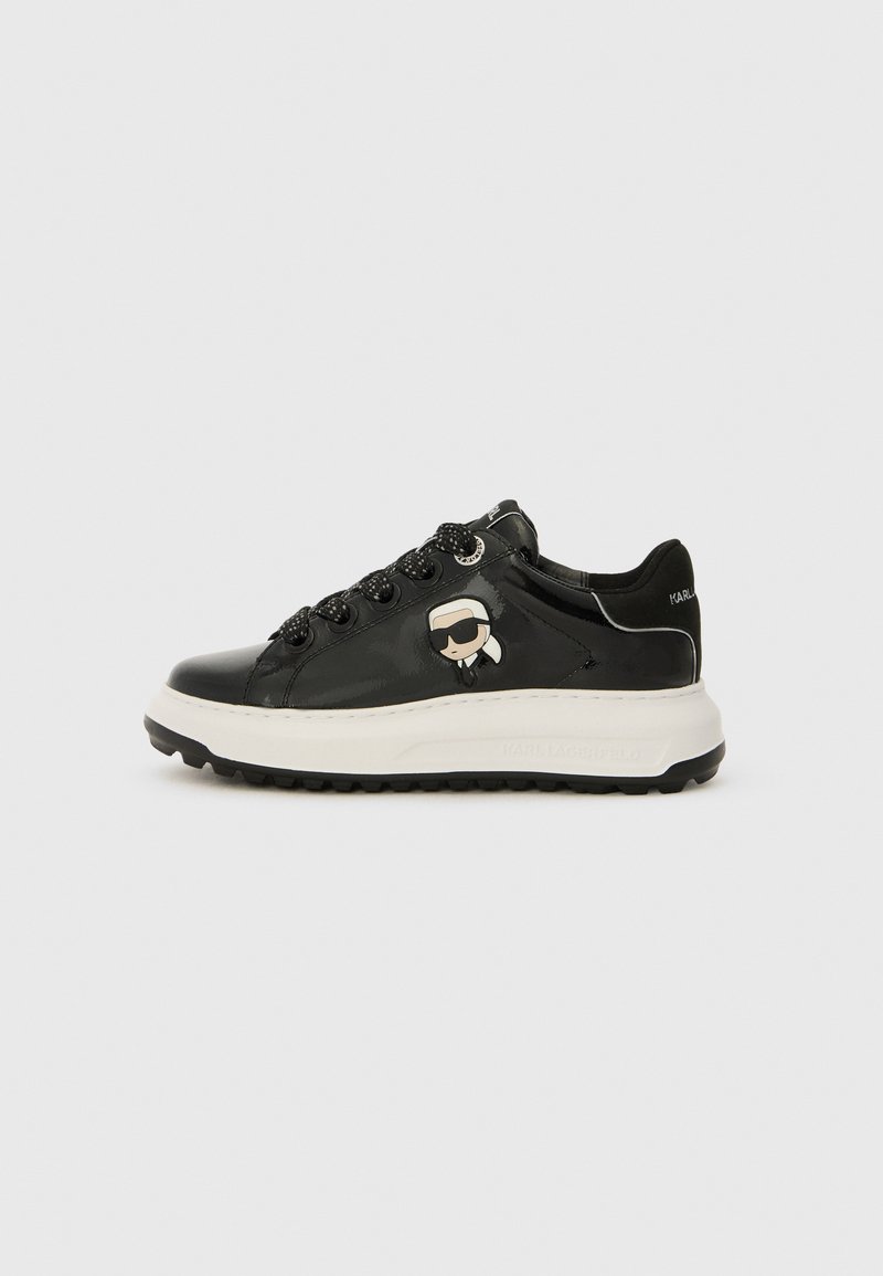 Black sneaker with glossy patent finish, featuring textured black laces, white midsole, and a cartoon character detail on the side.