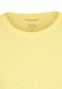 Lys gul bomulds t-shirt med rund halsudskæring, et lille orange accentmærke på bagsiden og en blød tekstur. Camel Active-logo på fronten.