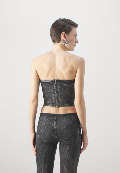 Black denim strapless top with a zip closure, fitted design, and faded texture. Paired with matching high-waisted skinny jeans.