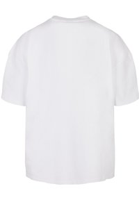 White oversized T-shirt made of cotton. Features a round neck, short sleeves, and a straight hem. Smooth texture, no visible patterns.