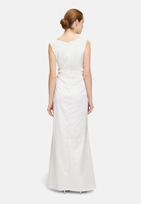 Robe blanche sans manches avec une silhouette ajustée, dos en V et texture satin lisse. Longueur au sol avec peu de détails et un design épuré.