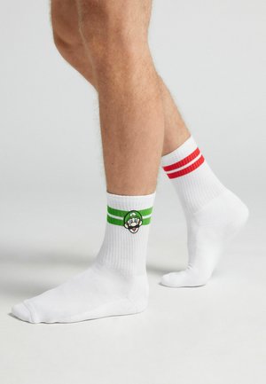 Weiße Baumwollsocken mit roten und grünen Streifen am oberen Ende, ausgestattet mit einem gestickten Charakter-Logo an der Seite.
