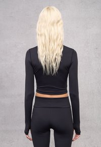 Schwarzes langärmliges Crop-Top aus glattem, dehnbarem Material. Hat ein passgenaues Design mit abgerundetem Saum. Wird mit passenden hochgeschnittenen Hosen getragen.