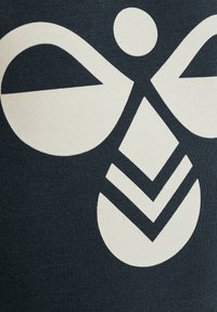 Mörk tyg med en strukturerad yta har en stor vit grafisk design, inklusive en cirkulär form och geometriska element under den.