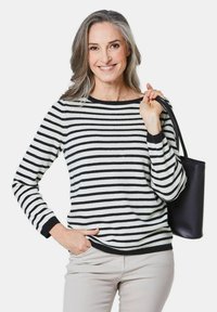 Zwart-wit gestreepte trui met een ronde hals en lange mouwen, gecombineerd met lichtbeige broeken en een zwarte totebag.