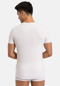 Hvid kortærmet T-shirt lavet af glat, let stof, med rund halsudskæring og en tætsiddende pasform set fra bagsiden af en mandlig model.