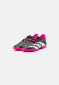 Scarpe da calcio con tomaia nera, caratterizzate da accenti bianchi e rosa, un motivo testurizzato e una suola in gomma rosa brillante.