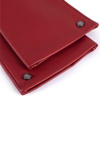 Clutch in pelle rossa con una superficie liscia, dotata di un design pieghevole e dettagli in metallo nero.