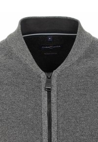 Grijze cardigan met een textuurgebreide stof, voorzien van een ritssluiting en een geribde kraag. Etiket leest "CASA MODA" met "Premium Katoen" eronder.