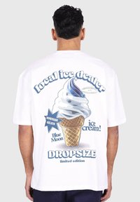 T-shirt en coton blanc avec un motif de cornet de glace bleu et blanc, accompagné des textes "vendeur de glace local", "gelato fait maison" et "édition limitée".