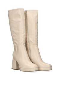 Botas beige hasta la rodilla hechas de material sintético, con cremallera lateral, tacón grueso y textura suave con base de plataforma.