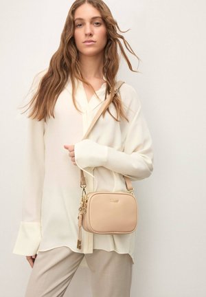 Beige Umhängetasche mit glatter Textur und goldfarbenen Metallakzenten, ausgestattet mit einem Reißverschluss und einem abnehmbaren Riemen für Vielseitigkeit.