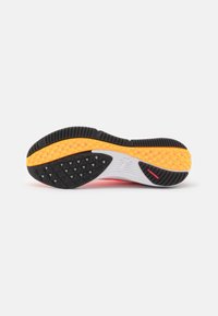 Suela de zapato de running con una vibrante goma negra y amarilla, con patrones de agarre texturizados y una sección blanca para soporte.
