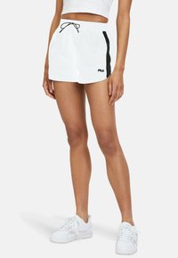 Pantaloni corti sportivi bianchi con una striscia laterale nera, vita elastica e cordoncino. Logo visibile sulla gamba sinistra.