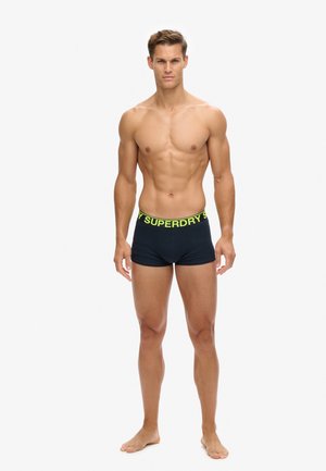 Boxer-culottes en coton bleu marine avec une ceinture élastique arborant le lettrage jaune "SUPERDRY". Texture lisse, design ajusté.