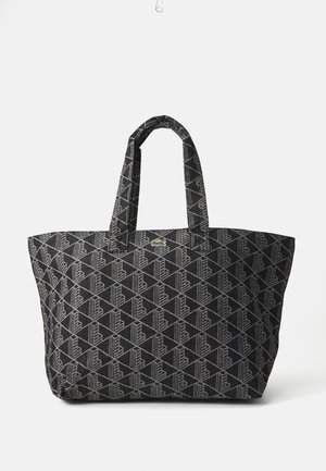 Borsa tote nera con un motivo geometrico grigio, dotata di due manici robusti e un piccolo logo verde come dettaglio. Realizzata in tessuto testurizzato.