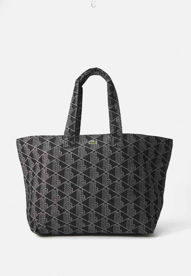 Svart totebag med et geometrisk mønster i grått, med to solide håndtak og en liten grønn logoakcent. Laget av teksturert stoff.