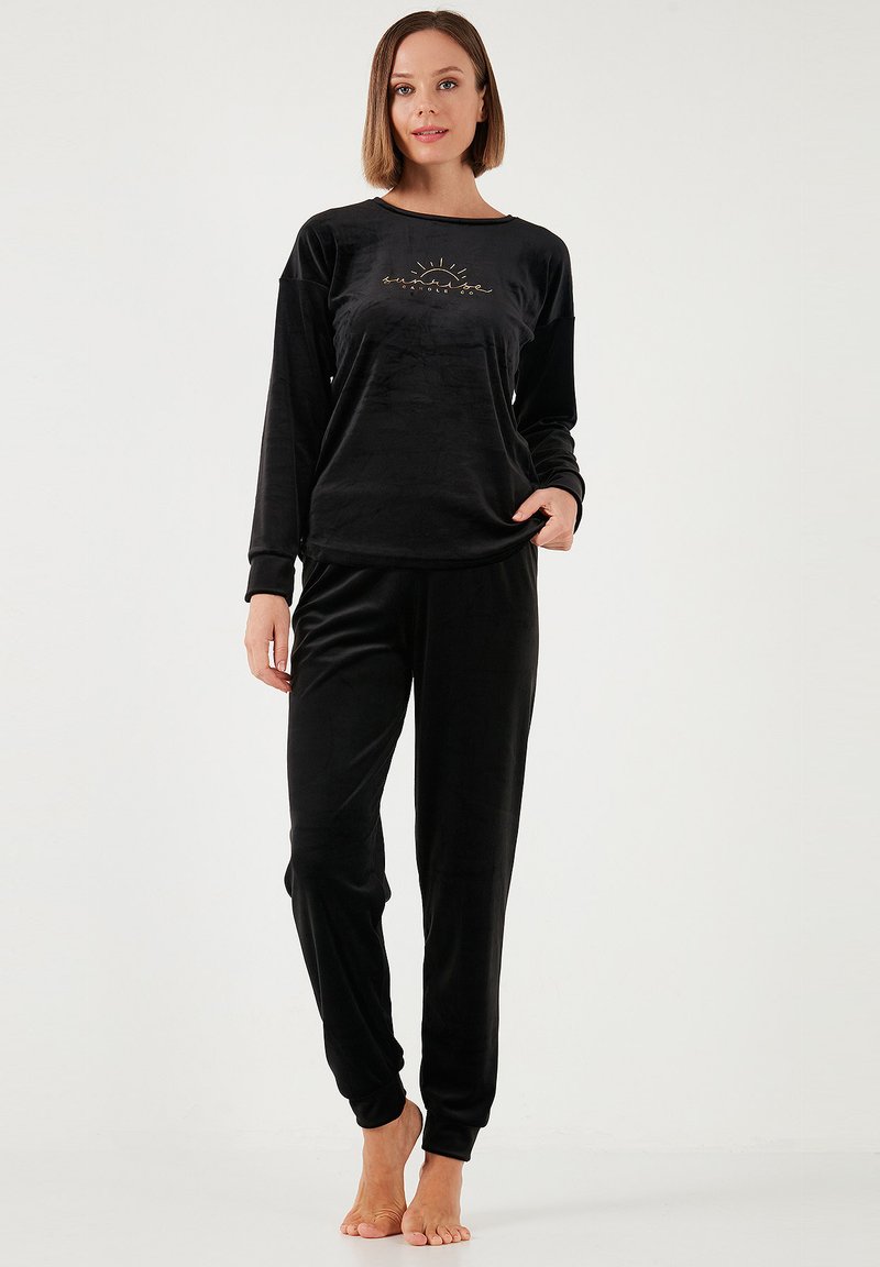 Zwart velours pyjama set met een lang aangesloten top met een eenvoudige zonafbeelding en bijpassende broek, zachte textuur en comfortabele pasvorm.