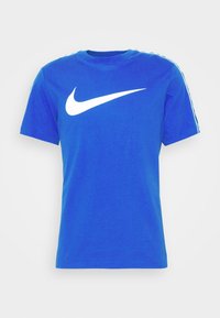 Sininen puuvillainen t-paita lyhyillä hihoilla, jossa on iso valkoinen Nike-swoosh-logo edessä ja valkoiset sivuraidat hihoissa.