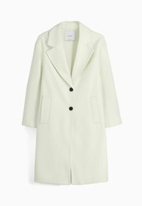 Ljusbeige kappa i ullblandning med krockad krage, två svarta knappar och sidofickor. Har en rak skärning och en medellång design.