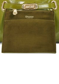 Green leather handbag with a shiny finish, featuring a detachable olive suede pocket, gold hardware, and embossed "Dune London" logo.