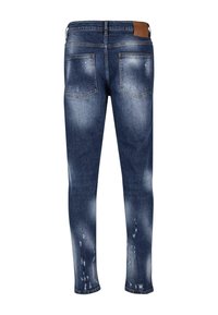 Tmavě modré džíny s úzkým střihem, které mají opotřebovaný vzhled se světlými nášivkami a odřenými detaily. Dvě zadní kapsy a hnědá nášivka na pase.