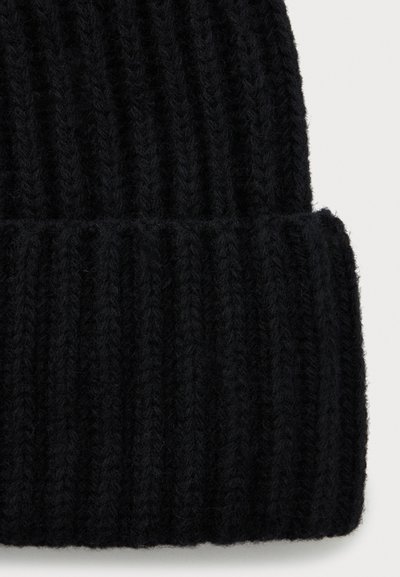 Mustmustera ribaga musta villane beanie, millel on volditud ääre, näidates detailset tekstuurset kudumist ja pehmeid karvaseid kiude.