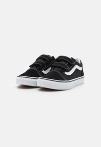 Black canvas sneakers with white accents, featuring a hook-and-loop strap closure, contrasting stitching, and a white rubber sole.