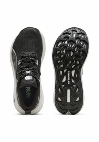 Zapatillas deportivas negras con parte superior de malla, detalles texturizados y acentos reflectantes. La suela tiene un patrón de superficie único para un mejor agarre.