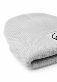 Gray ribbed knit beanie with a folded cuff and a label featuring a logo. The texture is soft and the fabric appears stretchy.