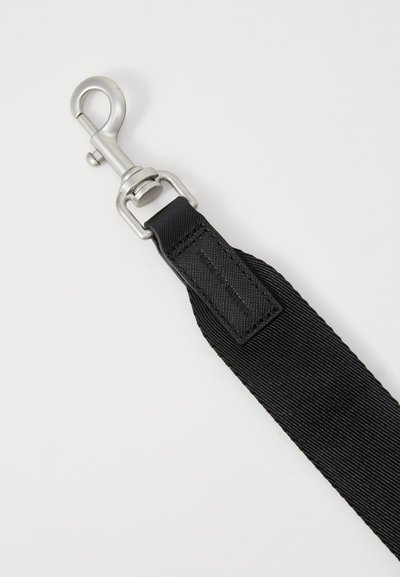 Sort justerbart rem lavet af tekstureret nylon med en sølvfarvet metalclip. Indeholder en rektangulær læderaccent nær clippen.