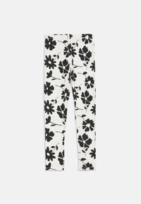 Leggings en coton extensible, dotés d'un fond blanc avec des motifs floraux noirs, comprenant diverses formes de fleurs et tiges.