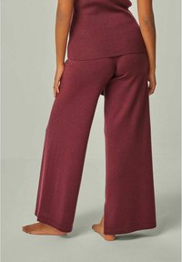Weite Hosen aus burgunderrotem Strickstoff, mit einer weichen Textur und entspannter Passform. Der Saum ist sauber verarbeitet und hat einen elastischen Bund.