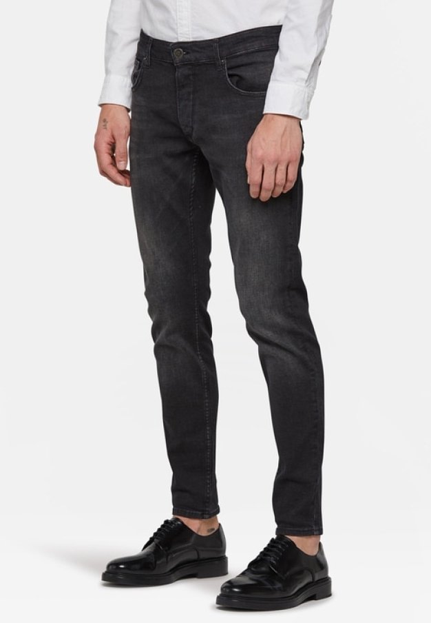 Mustat farkut slim fit -mallilla, jossa on viisi taskua, napitus ja hienovarainen kuluminen. Yhdistetty mustiin pukkenkiin ja valkoiseen paitaan.