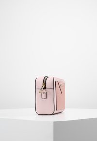Piccola borsa rettangolare in materiale testurizzato rosa chiaro, con zip dorata e bordi neri, dotata di un dettaglio con tasca laterale.