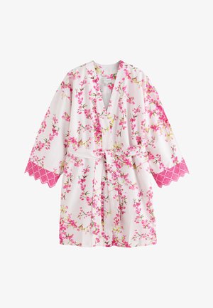 Valkoinen kukallinen kimono-ylipuku, jossa on vaaleanpunainen kirsikankukkakuvio ja vaaleanpunainen pitsireunus leveissä hihoissa, sidottu vyöllä vyötäröllä.