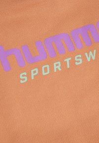 Jasnopomarańczowy materiał sportowy z prążkowaną teksturą. Zawiera duży fioletowy napis "humma" oraz mniejszy miętowozielony napis "SPORTSWEAR".