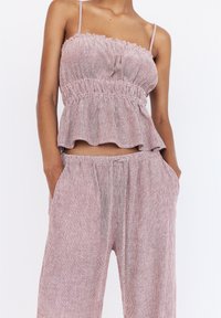 Red and white striped cropped top with ruffled edges and adjustable straps, paired with matching wide-leg pants featuring an elastic waistband.
