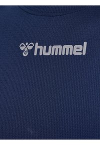 Mörkblått texturerat tyg med ribbat mönster, utrustat med en grå "hummel"-logotyp och ett bi-emblemet på övre vänstra delen.