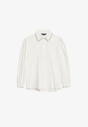 Hvit skjorte med lange ermer og klassisk krage, med dekorativ perlepynt langs kragen og knapper foran. Materialet ser glatt og stivt ut.