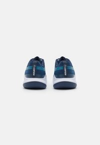 Marineblå sportssko med mesh-overdel, featuring teal striber, en hvid mellemsål og en tekstureret gummisål for godt greb.