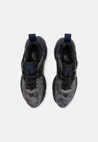 Pair of black and gray Nike sneakers with patterned fabric, reflective laces, and blue pull tabs, viewed from above on a white background.
