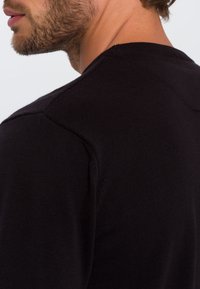 Czarny dziany sweter z okrągłym dekoltem, prążkowaną fakturą i detalami na szwie ramion. Posiada dopasowany, casualowy krój.