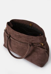 Hnědá semišová taška s měkkou texturou, s horním zipovým uzavřením, zlatými kovovými doplňky a dvěma rukojeťmi pro nošení. Vnitřek je černý.